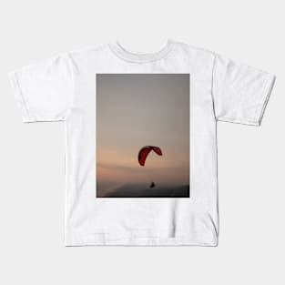 Paragliding in tandem over sea and beach at sunset Kids T-Shirt